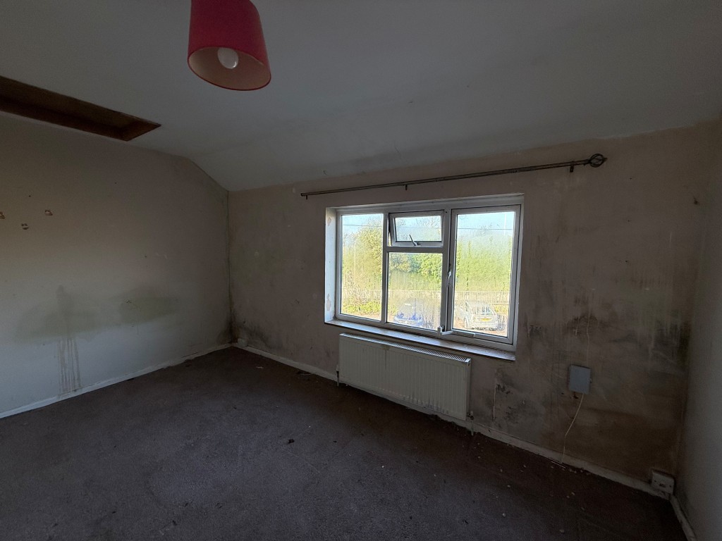Lot: 173 - THREE-BEDROOM TERRACED HOUSE FOR REFURBISHMENT LOCATED IN A CUL-DE-SAC - Main bedroom with slanted ceilings, window and radiator